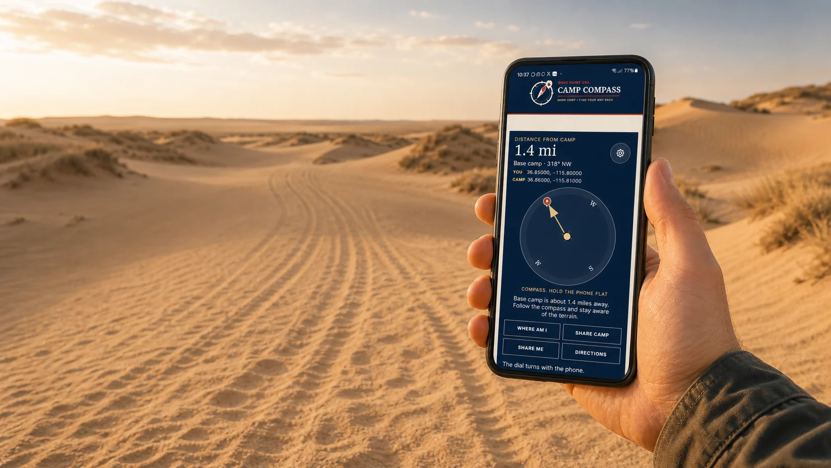 A rider holding Camp Compass open on a phone while tire tracks disappear across distant sand dunes