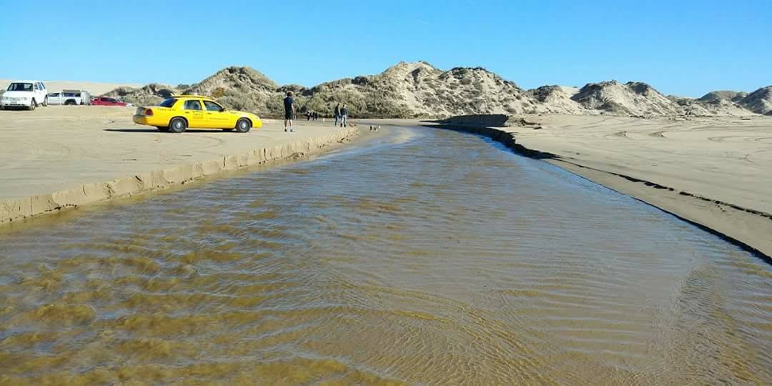 Vehicles parked near an easy shallow crossing of Arroyo Grande Creek at Oceano Dunes