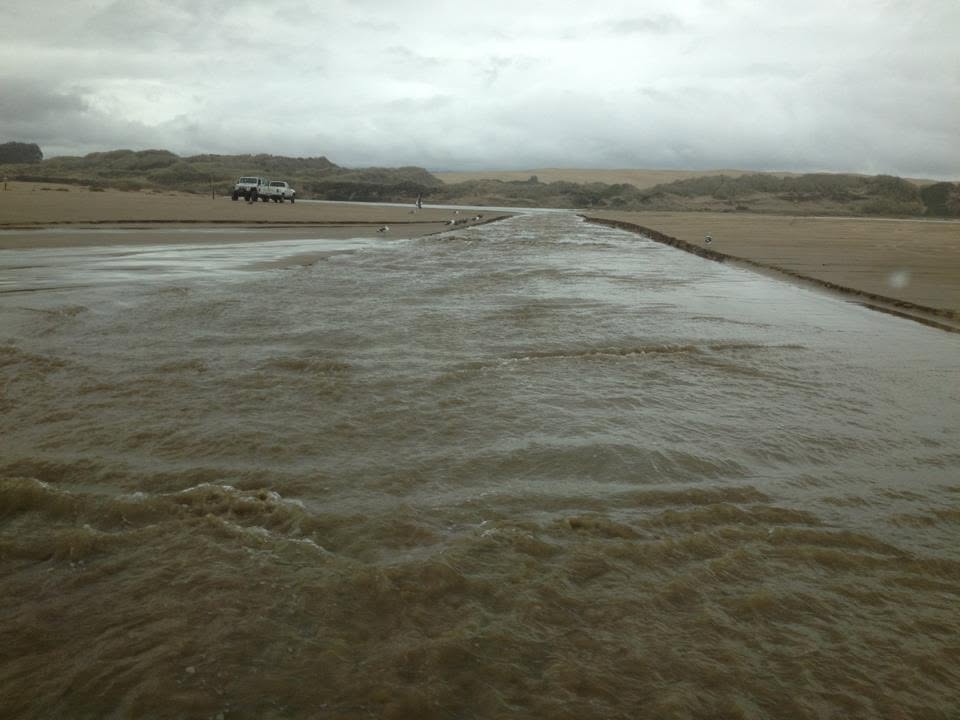 Arroyo Grande Creek running high and fast with muddy floodwater at Oceano Dunes