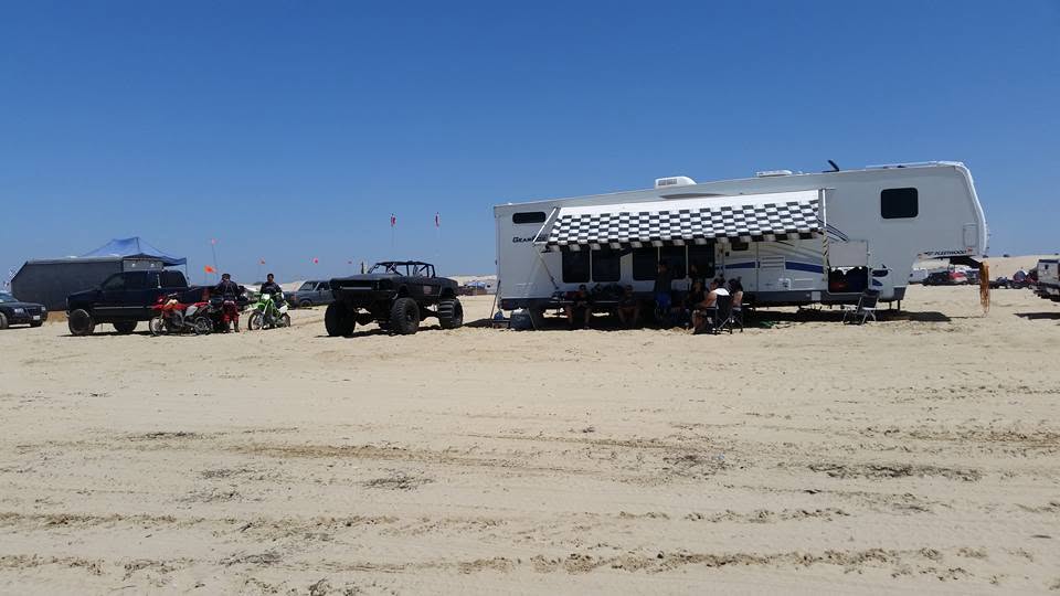 Fifth wheel trailer with dirt bikes and a buggy parked at a beach camp at Oceano Dunes
