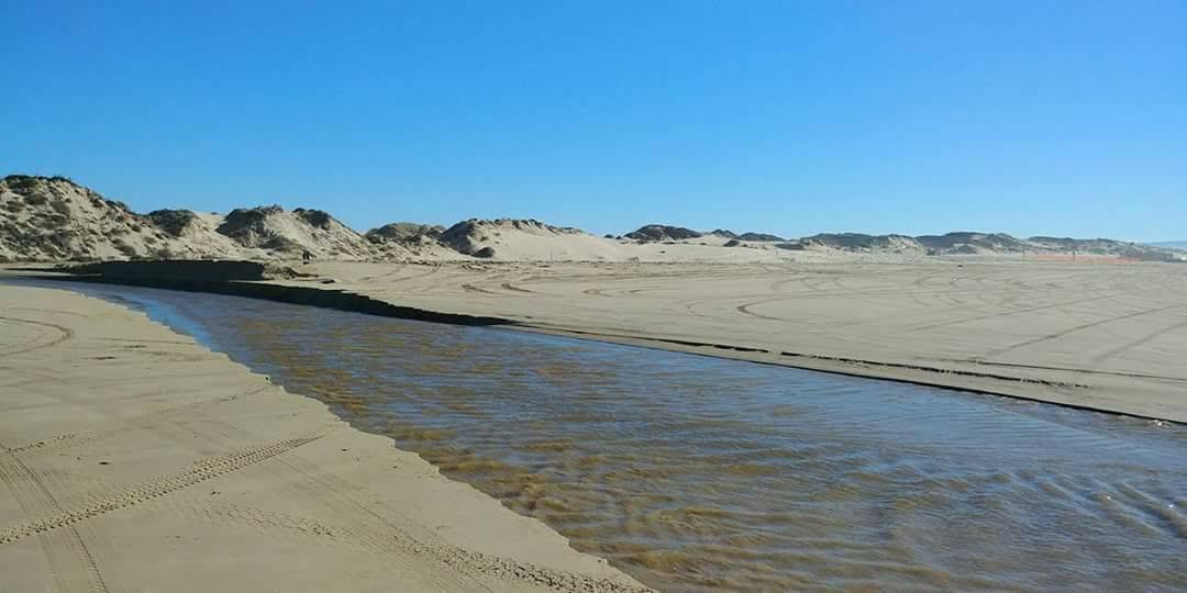 Arroyo Grande Creek calm and shallow at low tide with wide exposed sand at Oceano Dunes, California