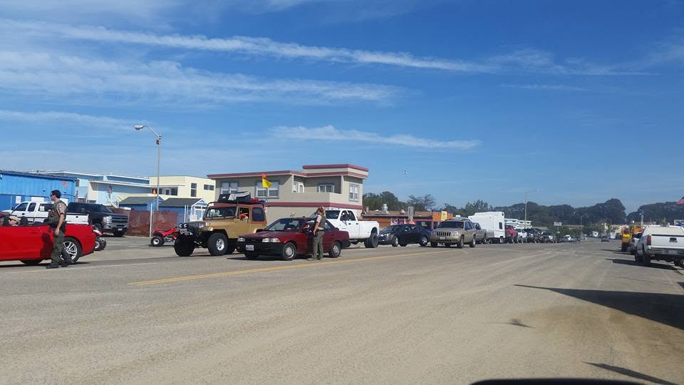 Vehicles lined up at the entrance gate with a park ranger at Oceano Dunes
