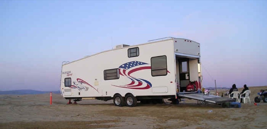 Fifth wheel trailer camped on the beach at dusk