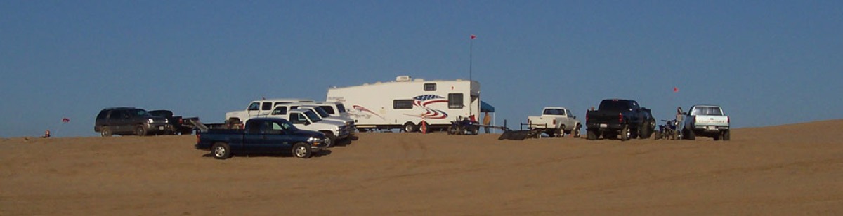 RVs and trucks camped along a dune ridge